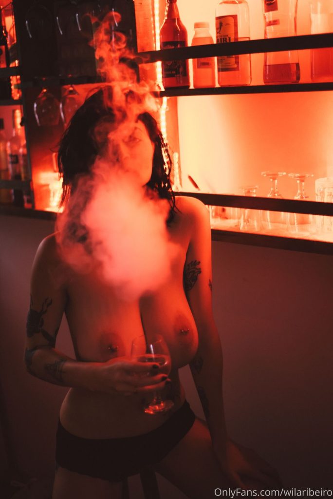 A topless woman with smoke coming out of her mouth and most of face covered with it