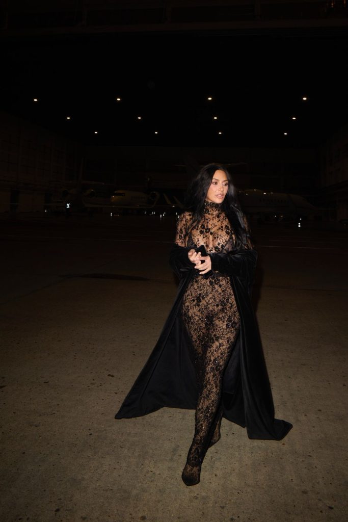 Far away view of Kim Kardashian walking in a lace outfit at night
