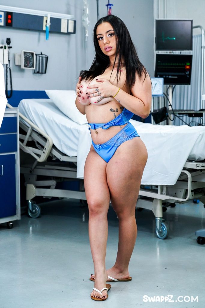 Full body frontal of Latina nurse standing at an angle and grabbing her breasts