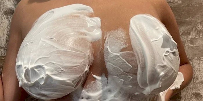 Close up of a woman's breasts covered with cream