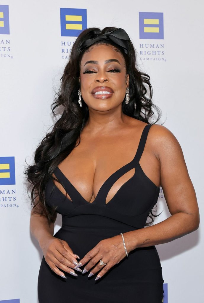 Close up of black woman with a big smile on her face wearing a low cut dress.