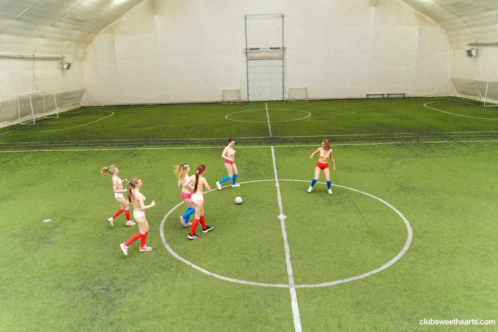 Far away and looking down on an indoor Soccer pitch with a group of topless women playing a match.
