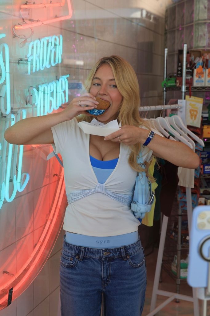 Sydney Sweeney eats a cookie inside a store.