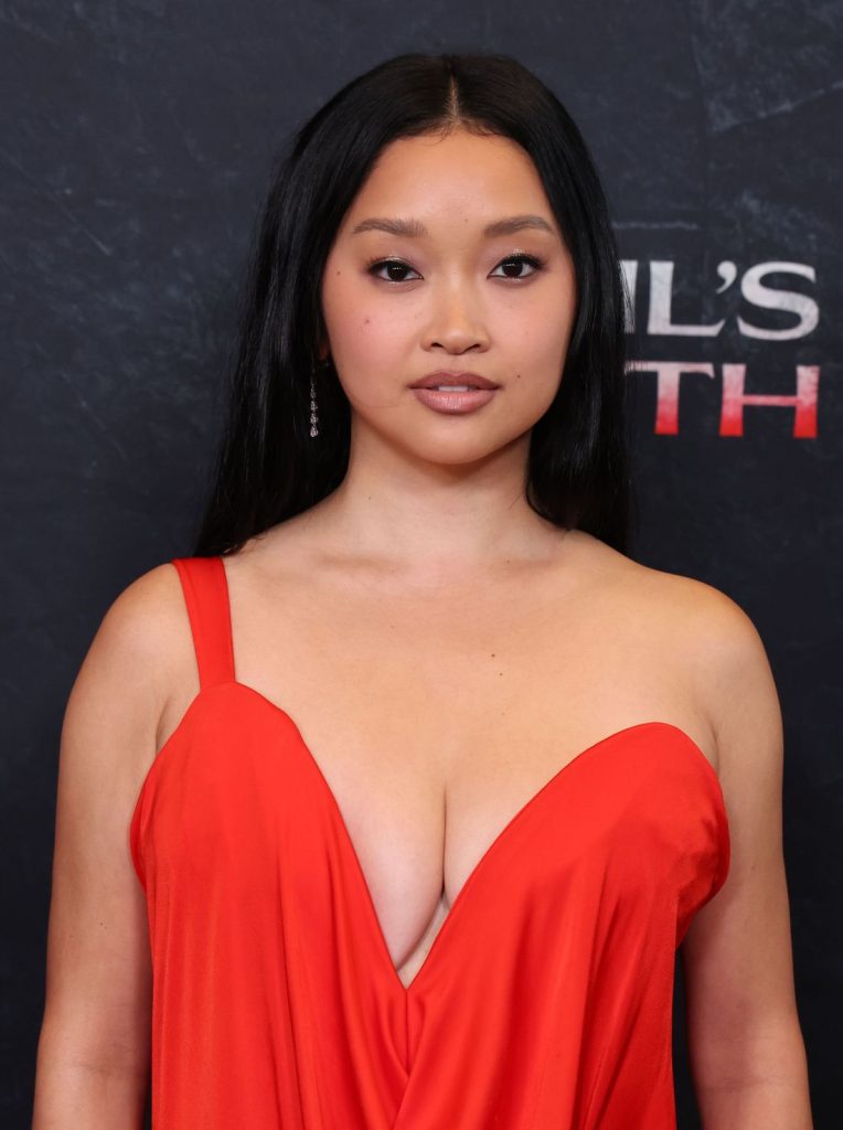 Asian woman with long black hair wearing a deep red, low-cut dress stands in front of a dark background with partial white and red text.