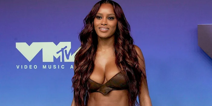 Ciara Miller poses in front of a blue MTV Video Music Awards backdrop in tiny leather top.