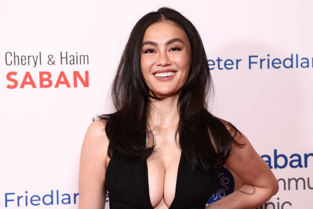 Asian woman with full wearing a black plunging thater-neck gown smiles at the camera.