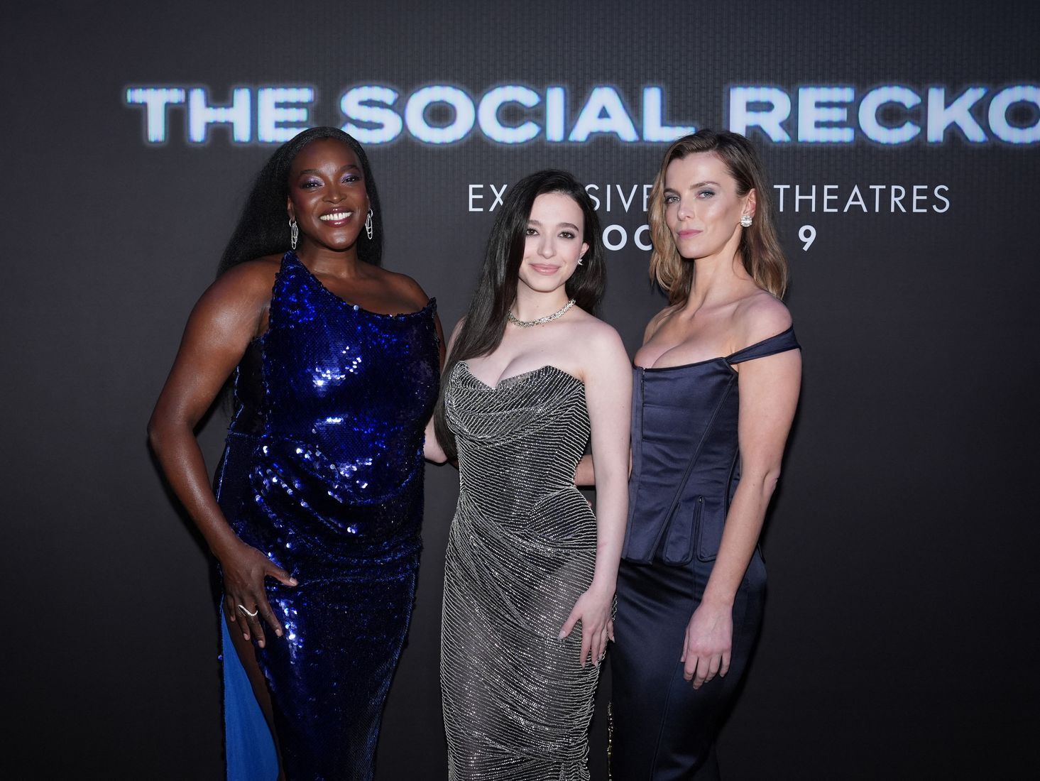 Three women posing in front of a backdrop for the film The Social Reckoning.