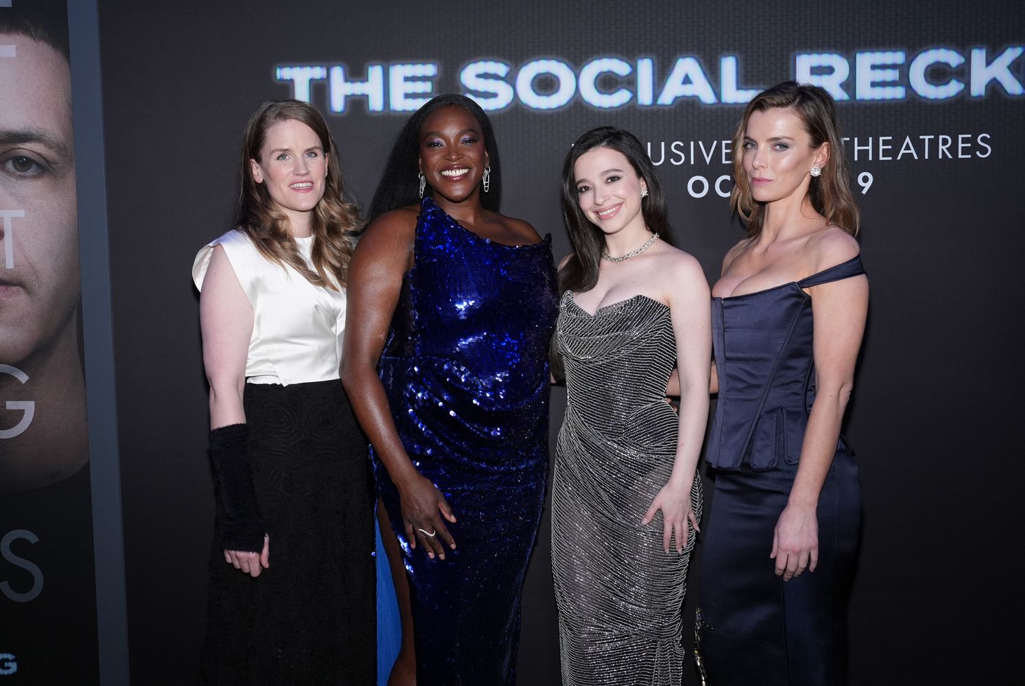 Four women pose for a photo in front of a movie poster for The Social Reckoning.
