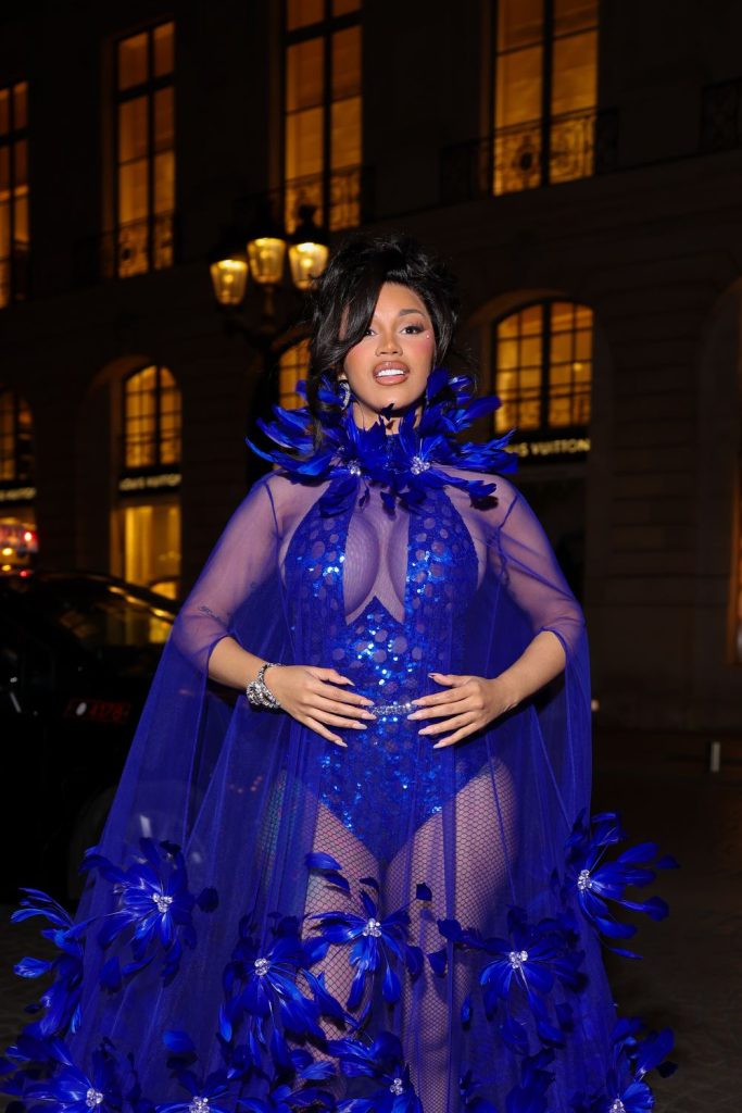 Cardi B wearing a sheer, blue sequined bodysuit with a matching feathered cape.