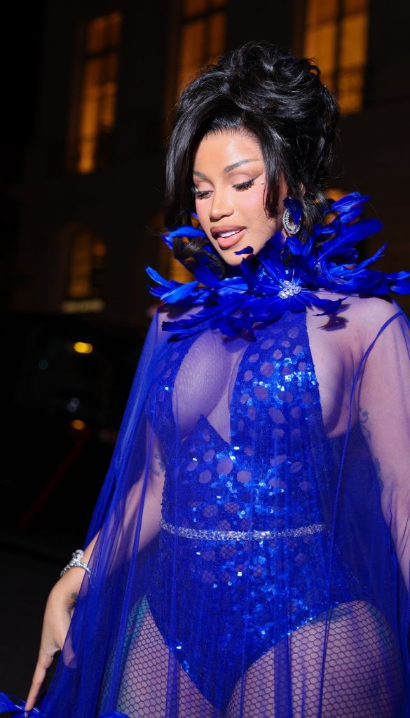 Cardi B wearing a royal blue sequined bodysuit with a matching sheer cape and a feathered collar.
