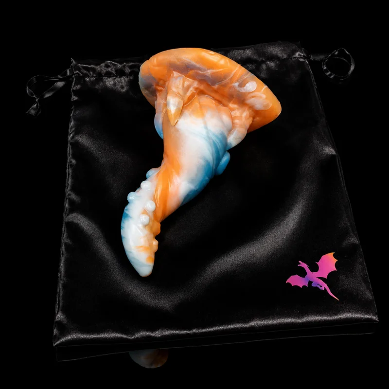 Dragon Dildo® Wyrm’s Own silicone sculpt in swirled orange, white and blue lying on a black satin bag with a pink dragon logo